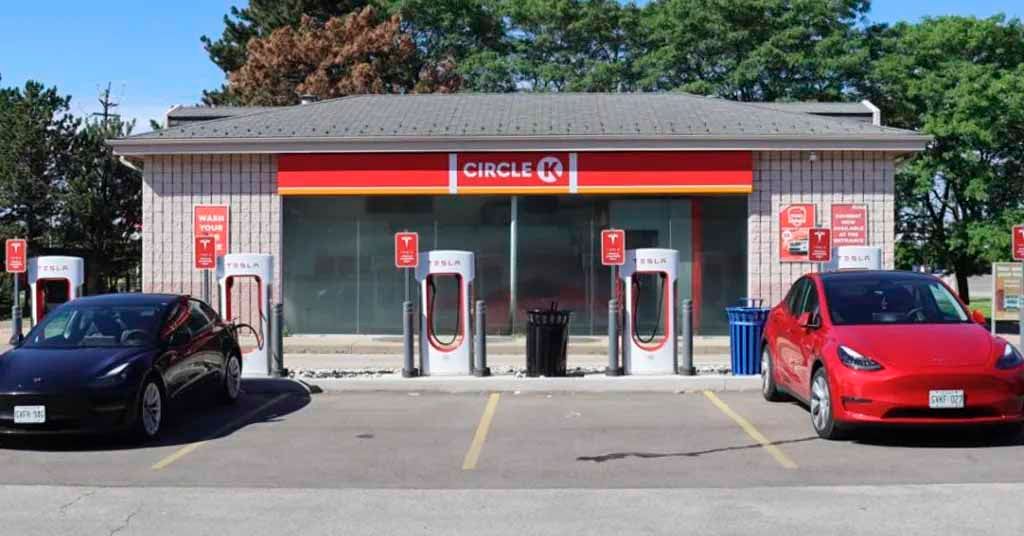 Two electric cars are parked in front of a circle k gas station