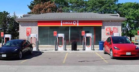 Two electric cars are parked in front of a circle k gas station