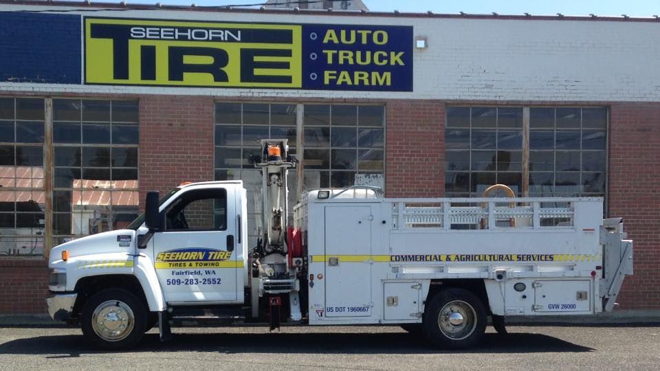 A white truck is parked in front of a tire shop