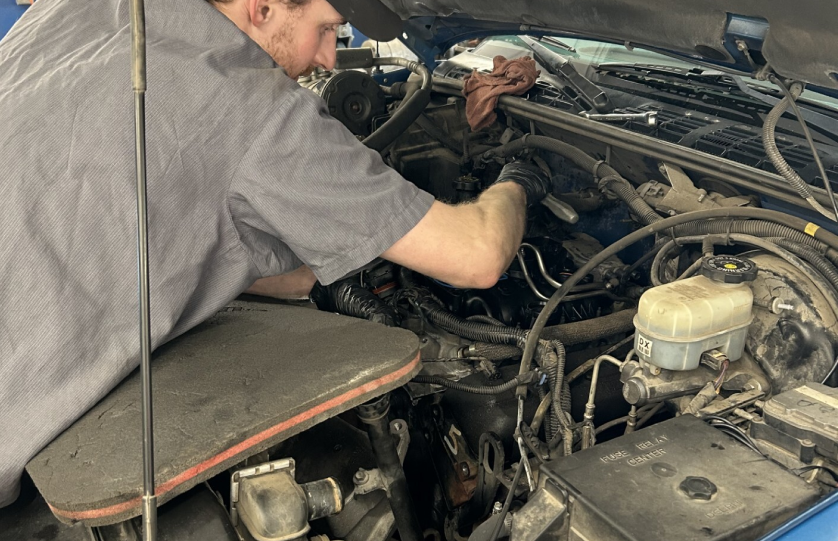 Technician working under hood of vehicle | Rockford Auto Inc