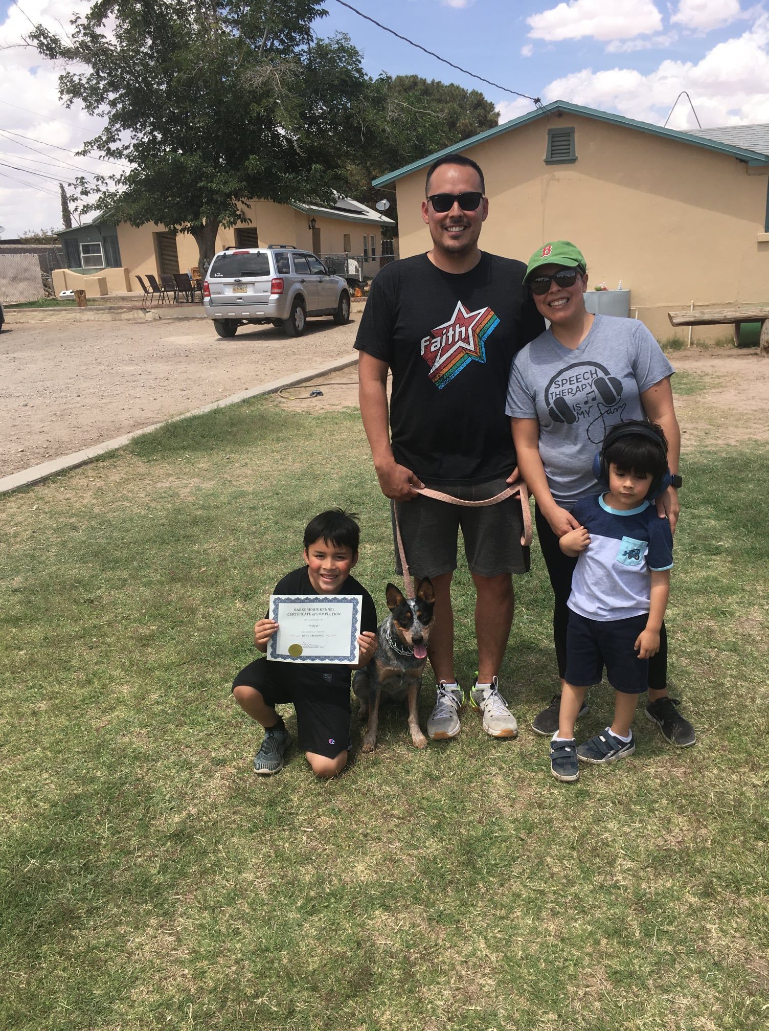 Family with two children and a dog, posing for a photo outdoors.