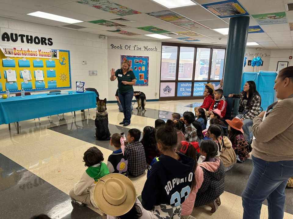 Teacher giving a presentation to a group of children with a dog in a classroom.
