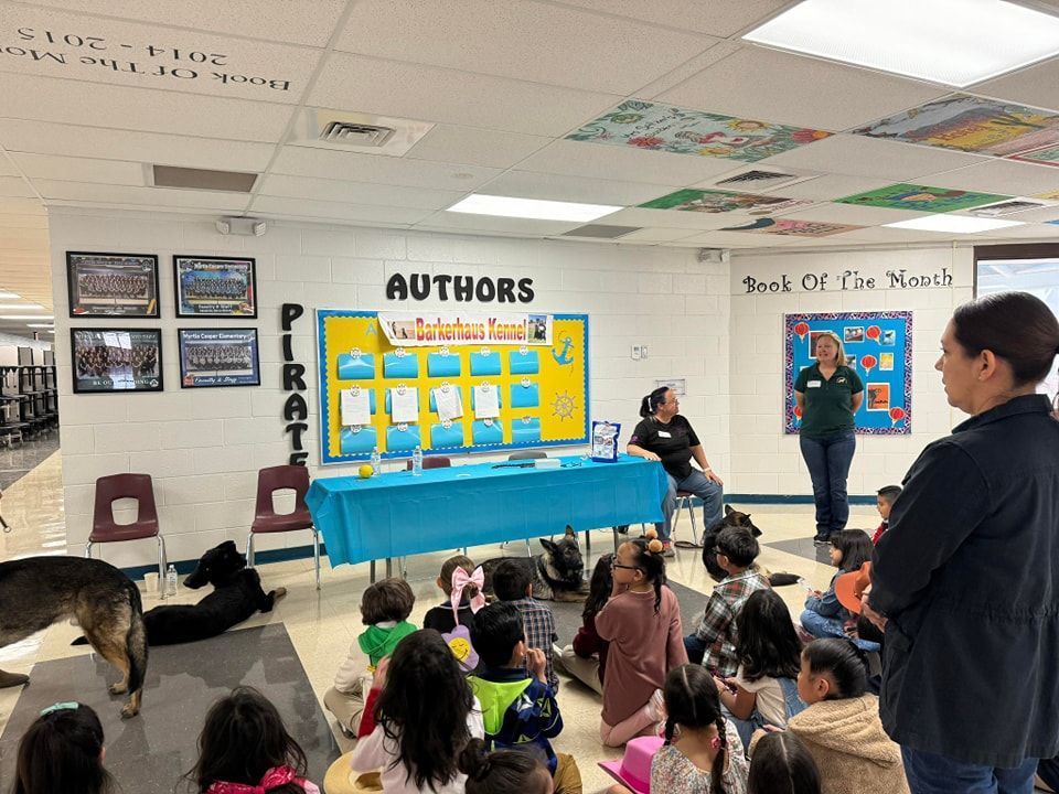 Children's book reading event at a library. People are gathered around a table with books and a display.
