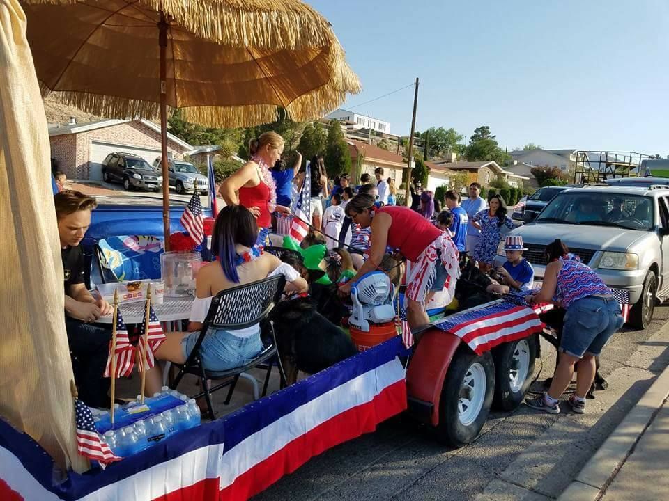 People decorating a patriotic float with red, white, and blue decorations for a parade.