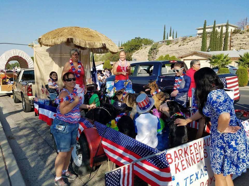 People and dogs on a parade float decorated with American flags.
