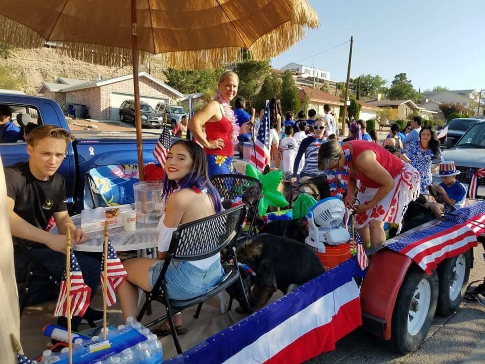 People celebrating on a float decorated with red, white, and blue, likely a 4th of July event.