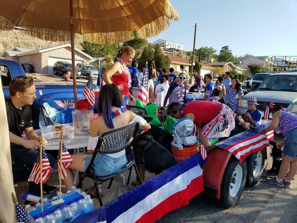 People on a decorated trailer for a parade with American flags, red, white, and blue décor.