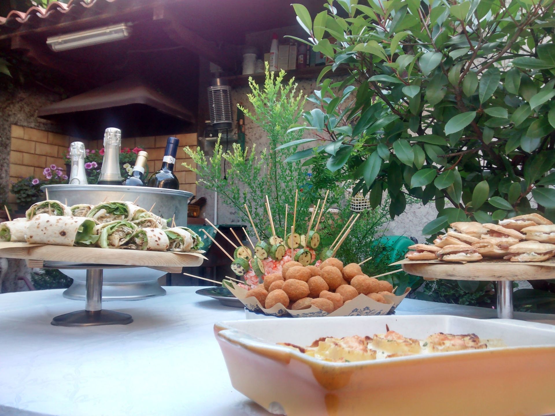 Tavolo da buffet con un assortimento di pasticcini, frutta e piatti salati in un ambiente da pranzo illuminato da luci soffuse.