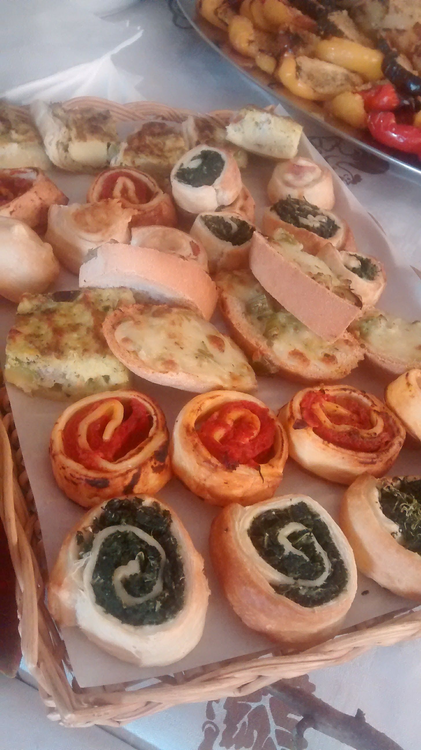 Un assortimento di antipasti aperti su un vassoio, tra cui fette di formaggio, pomodoro e olive.