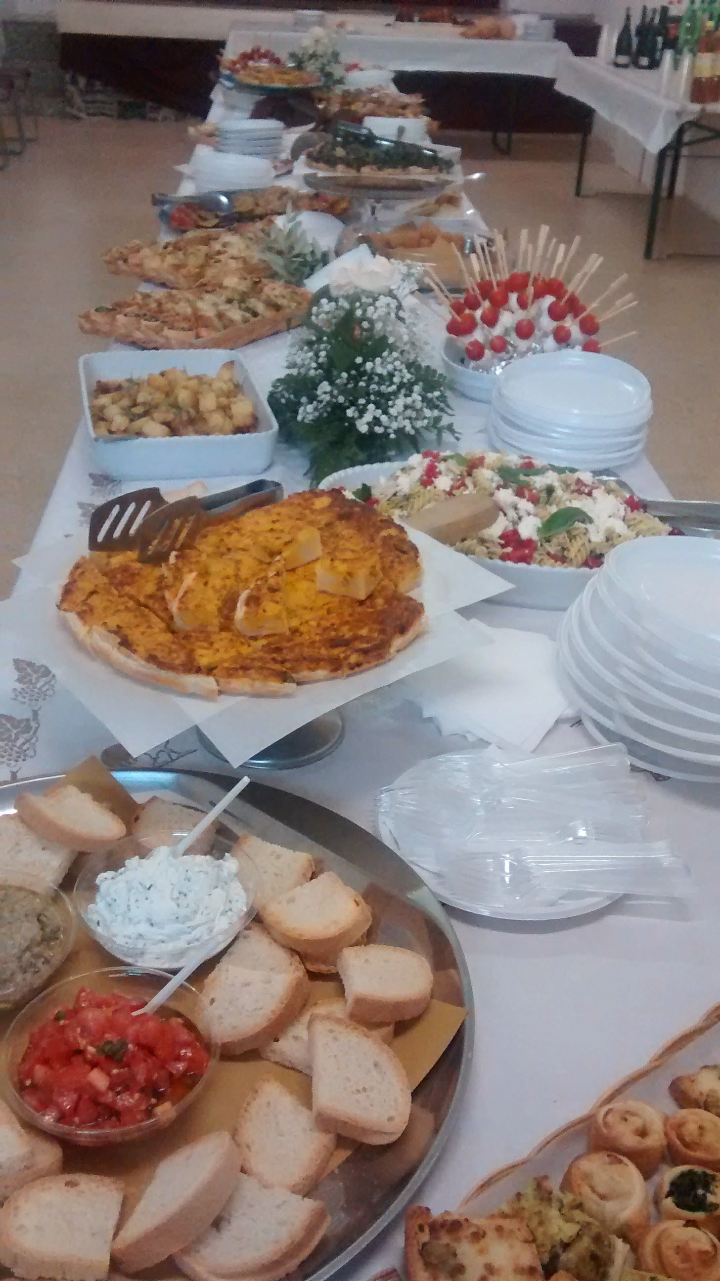 Tavolo da buffet con un assortimento di piatti, pane, insalate e vassoi disposti per il servizio.