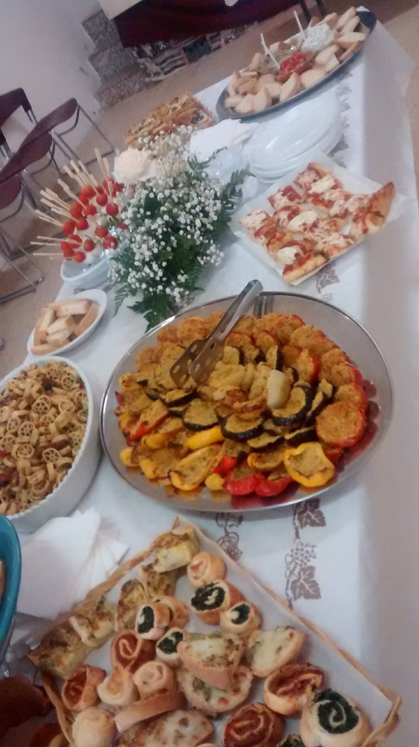 Tavolo apparecchiato con un assortimento di antipasti e insalate, tra cui un piatto centrale con verdure colorate tagliate a fette.