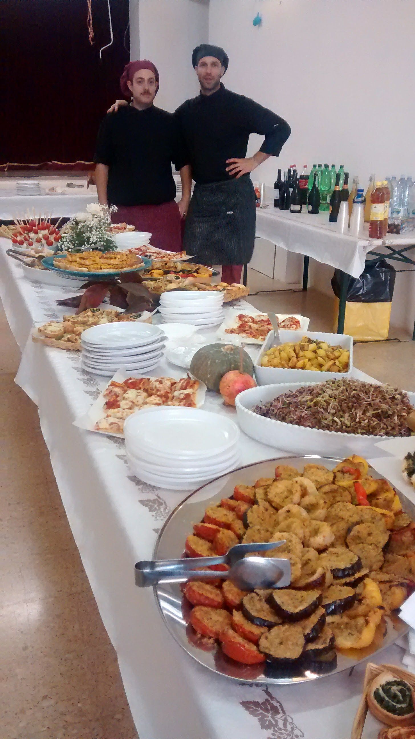 Un buffet con piatti assortiti e due persone in piedi dietro di esso in una sala da pranzo.
