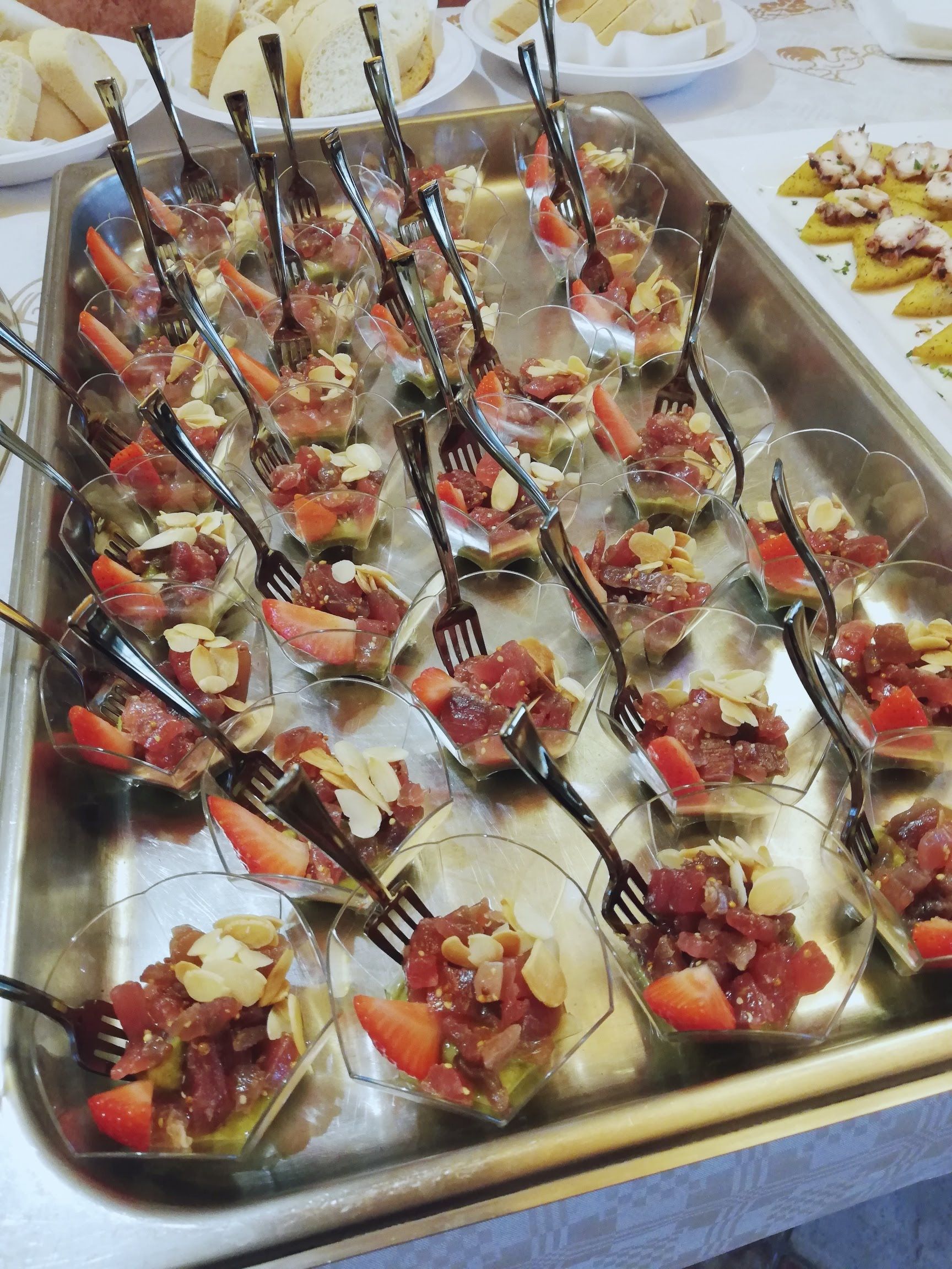 Vassoio di cucchiaini da antipasto conditi con salsa rossa ed erbe aromatiche, in un buffet con servizio di catering.