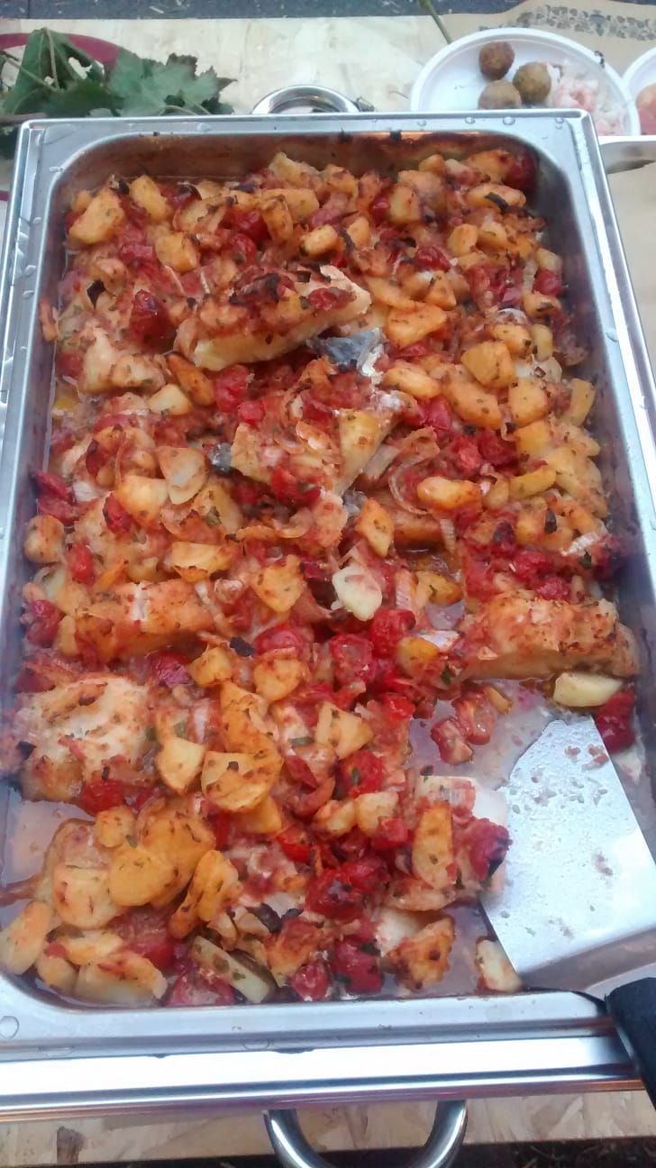 Vassoio di patate arrosto con condimento rosso e verdure tritate in un piatto da buffet