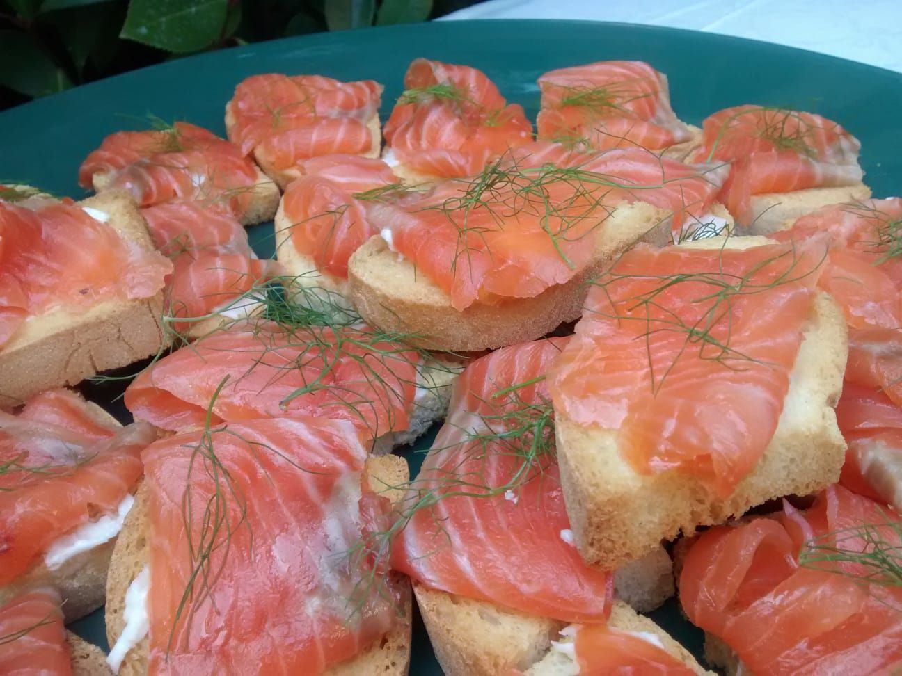 Tartine con salmone su pane tostato disposte su un vassoio e guarnite con aneto.