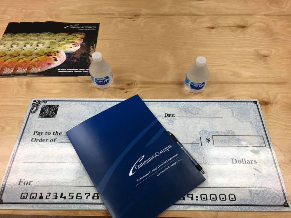 giant check with folder on top of it sitting on wooden table with two water bottles