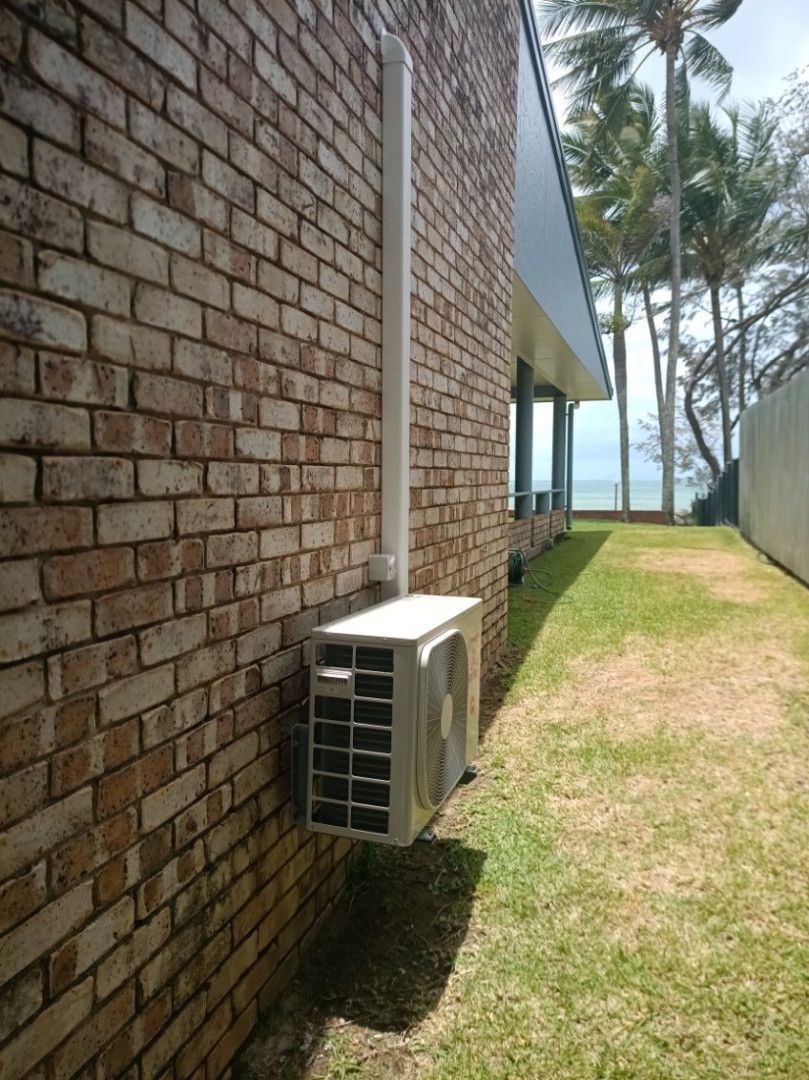 An Air Conditioner is Mounted on the Side of a Building — Instant Spark Electrical in Proserpine, QLD