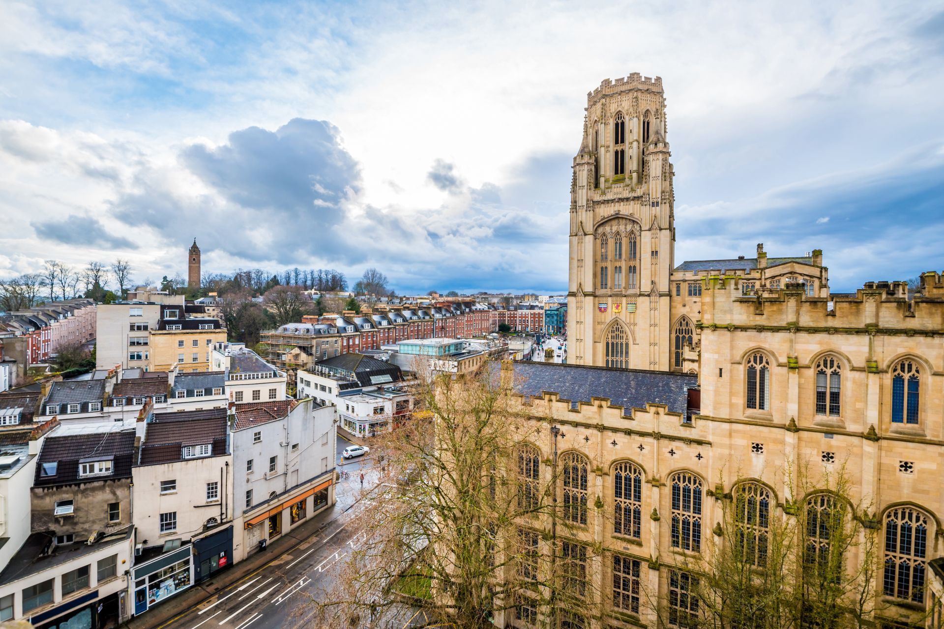 An aerial view of a large building with a clock tower in the middle of a city.