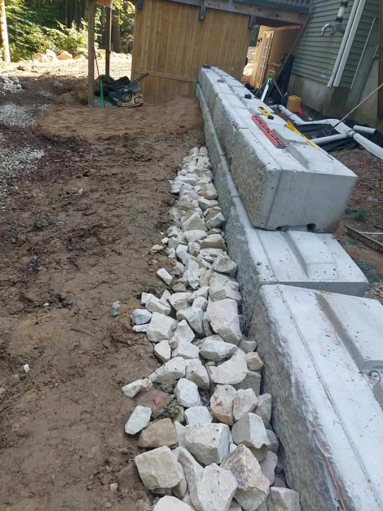 A concrete wall is being built next to a pile of rocks.