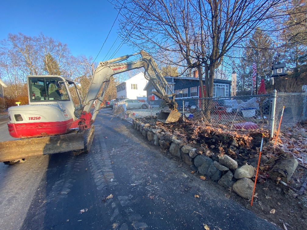 A red and white excavator is parked on the side of a road.