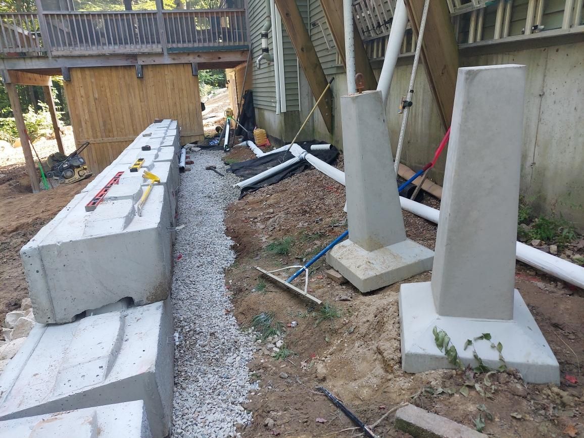 A group of concrete blocks are sitting in the dirt in front of a house.