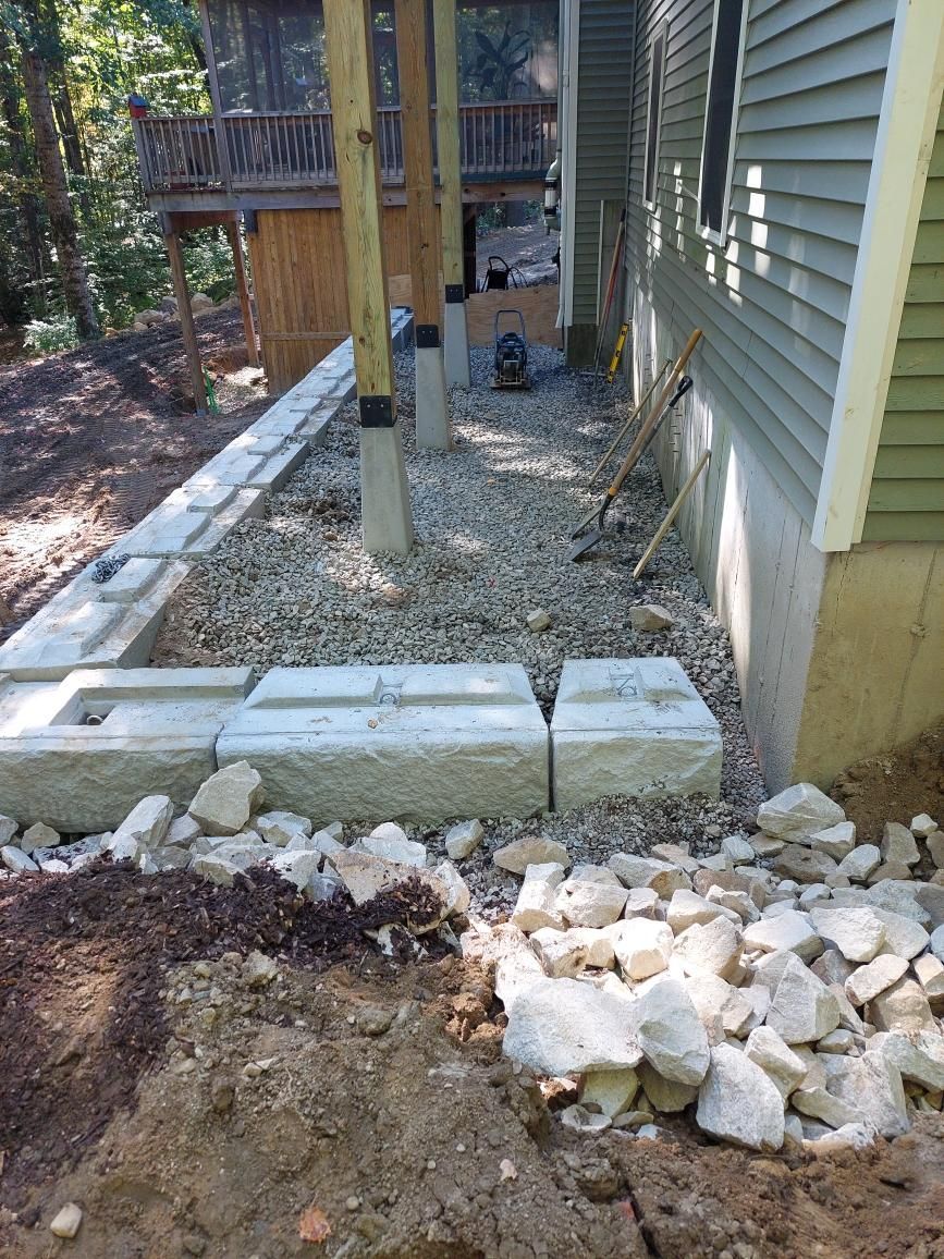 A stone wall is being built in front of a house.