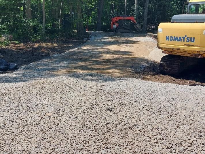 A yellow komatsu excavator is sitting on a gravel road.