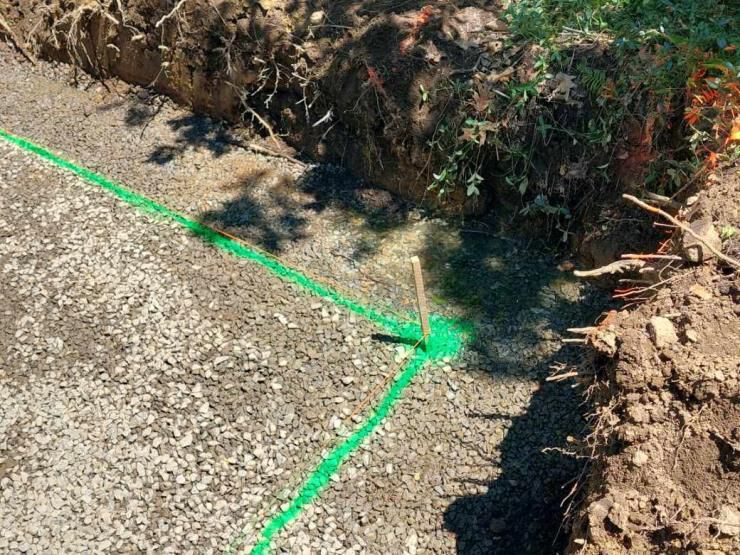 A green line is being drawn on the ground next to a hole in the ground.