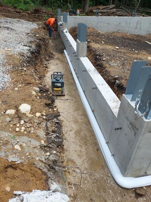 A man is working on a concrete wall in a dirt field.