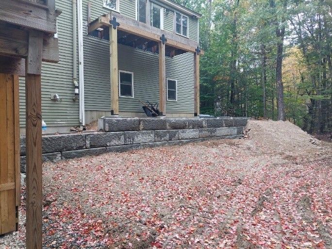 The backyard of a house with a stone wall and a wooden deck.