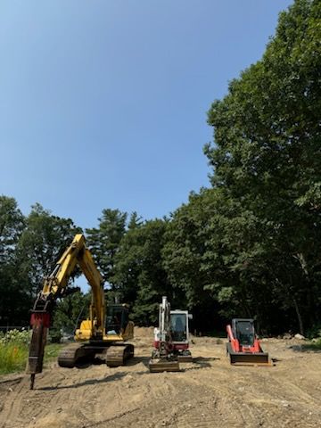 A group of construction vehicles are parked in a dirt field.