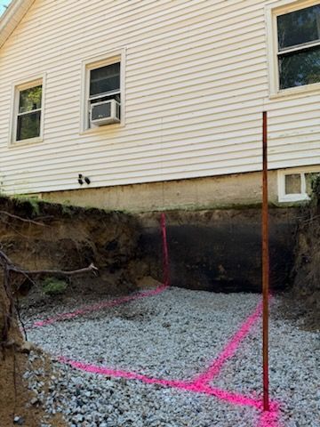 A house with a hole in the ground in front of it.