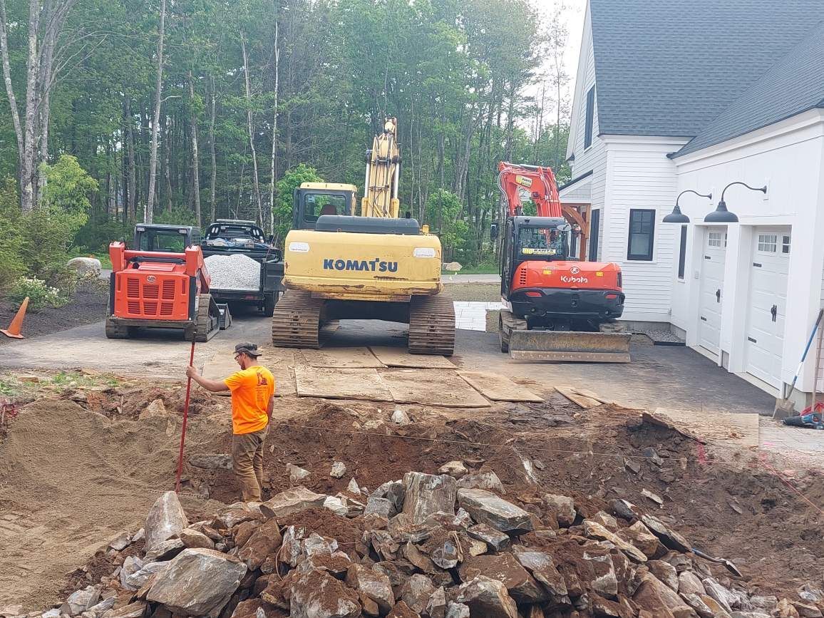A group of construction vehicles are parked in front of a house.
