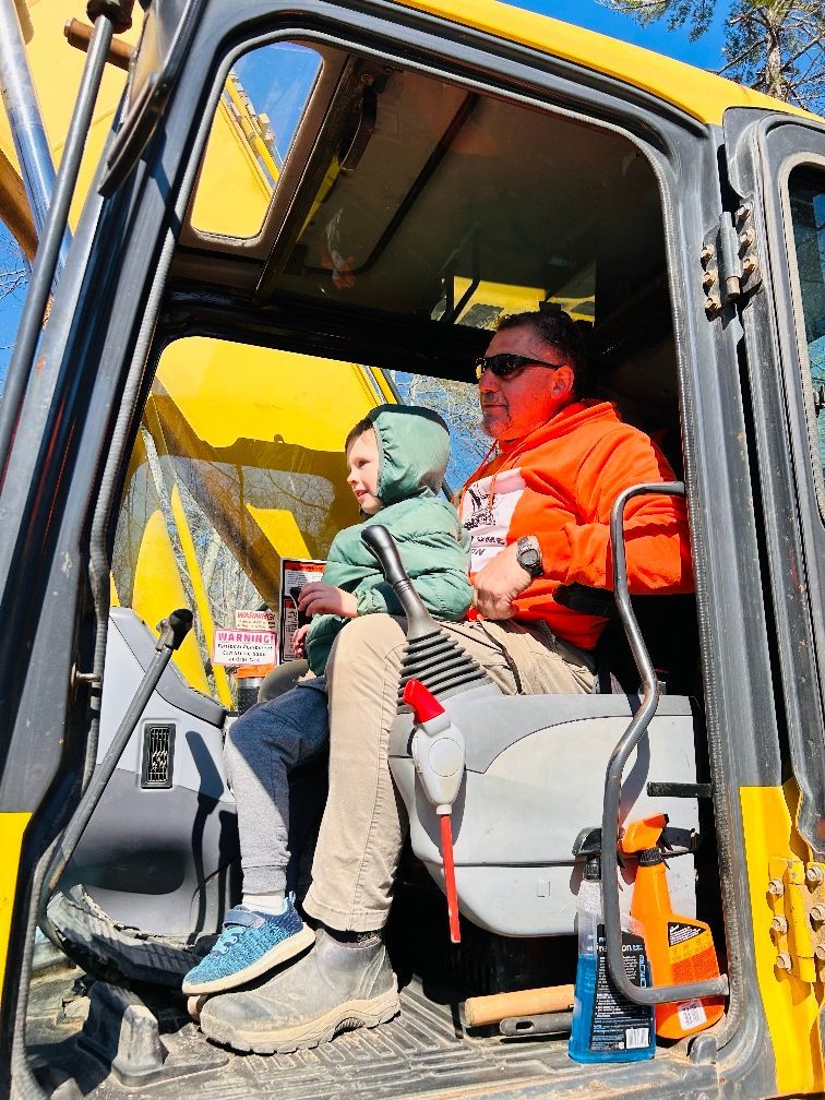 A man and a child are sitting in the driver 's seat of a construction vehicle.