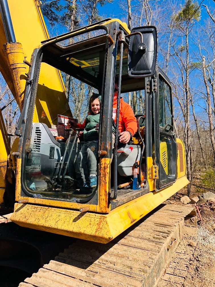 A man and a child are sitting in a yellow excavator.