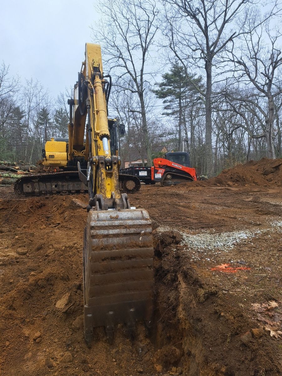 A yellow excavator is digging a hole in a dirt field.