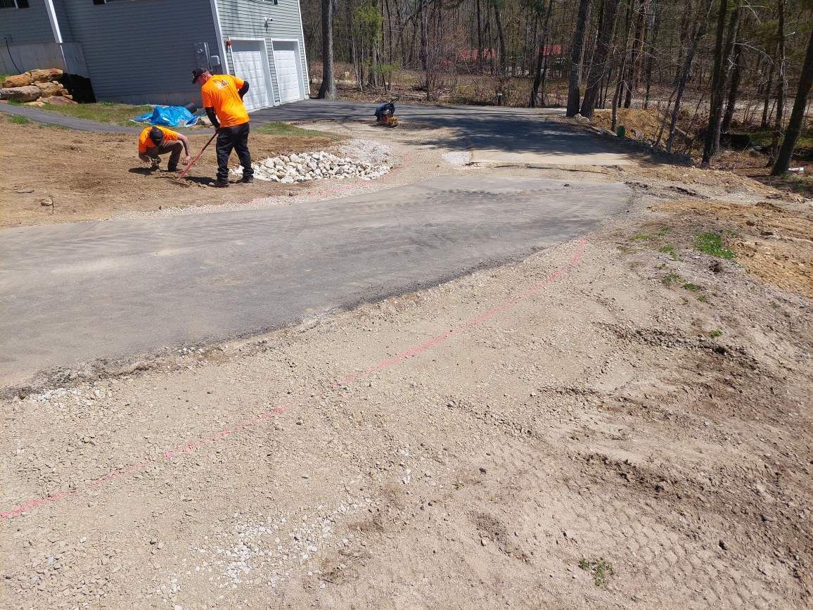 A man in an orange shirt is standing on the side of a road.