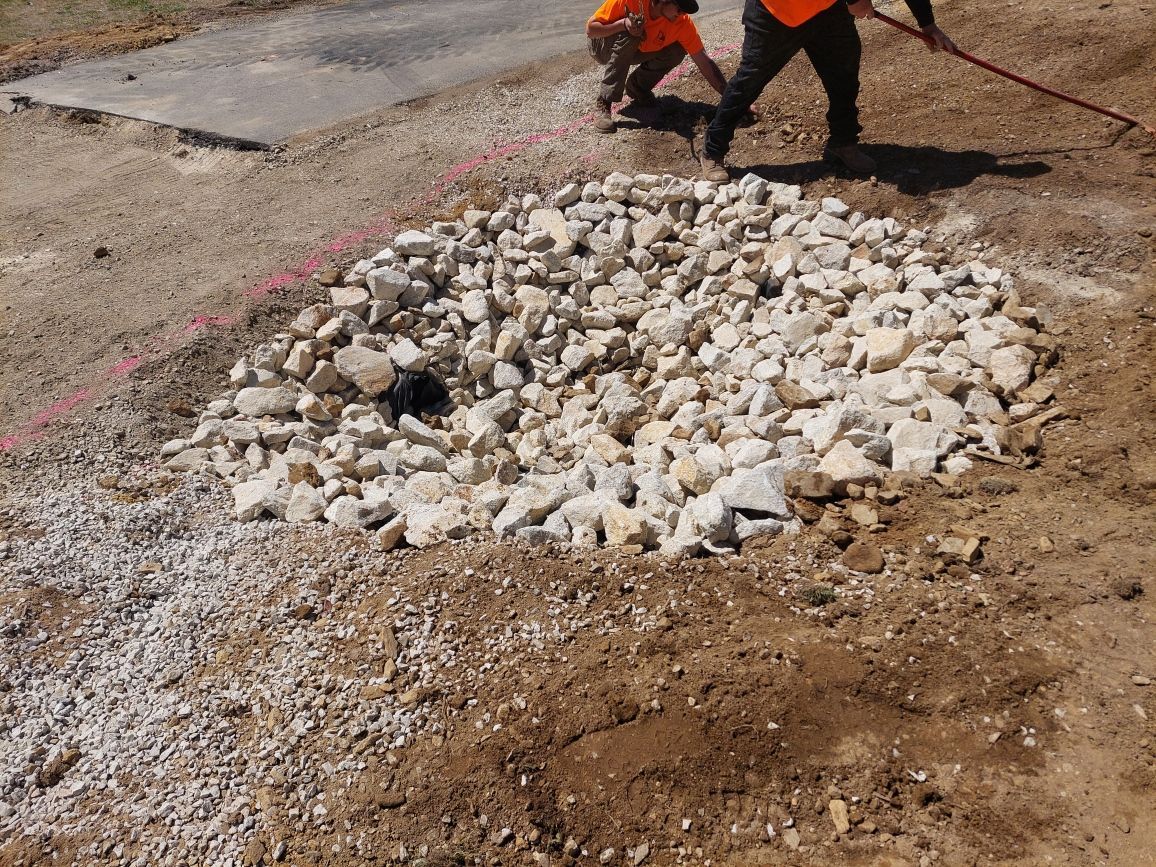 Two construction workers are working on a pile of gravel.