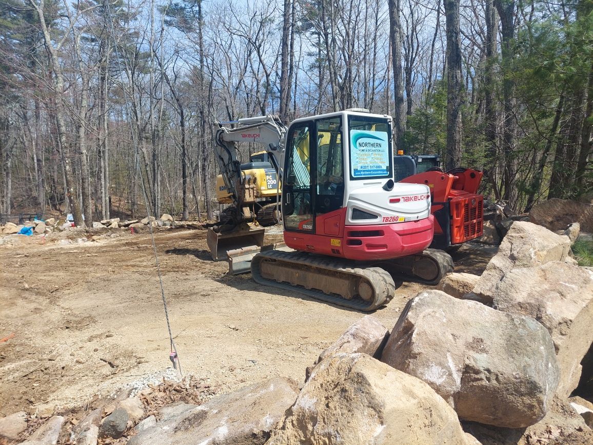 A red excavator is parked next to a yellow excavator in a dirt field.