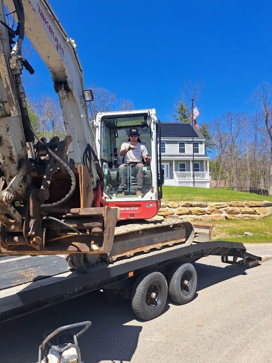 A man is driving an excavator on a trailer.