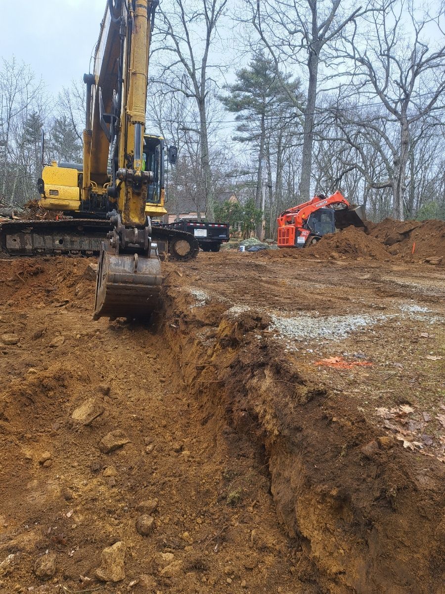 A large yellow excavator is digging a hole in a dirt field.