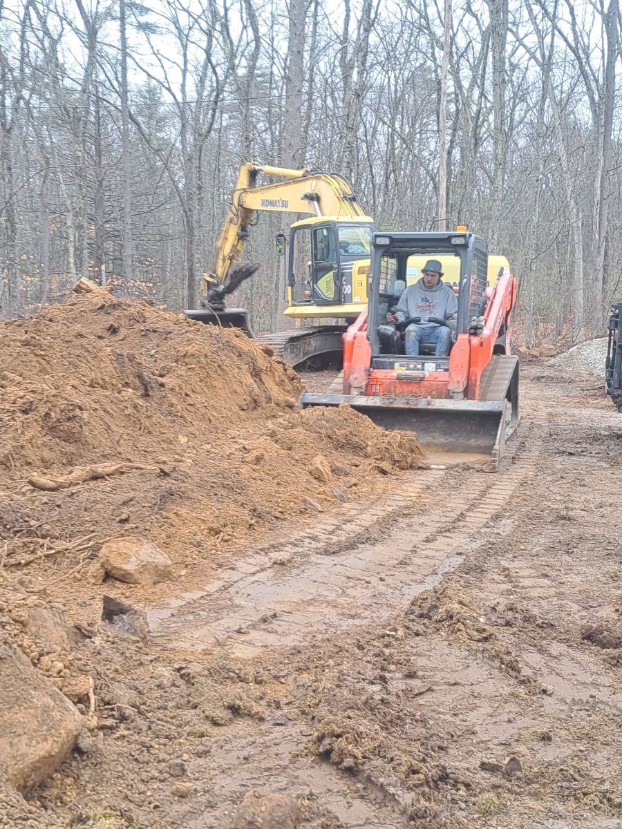 A man is driving a bulldozer on a dirt road.