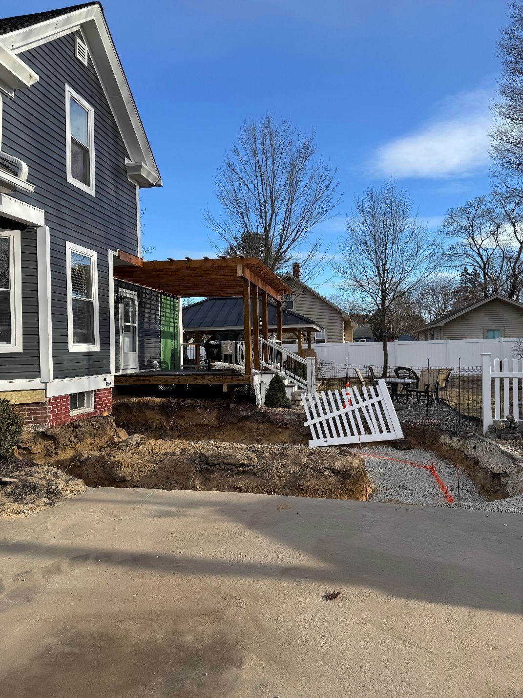 A black house with a white fence in front of it is under construction.