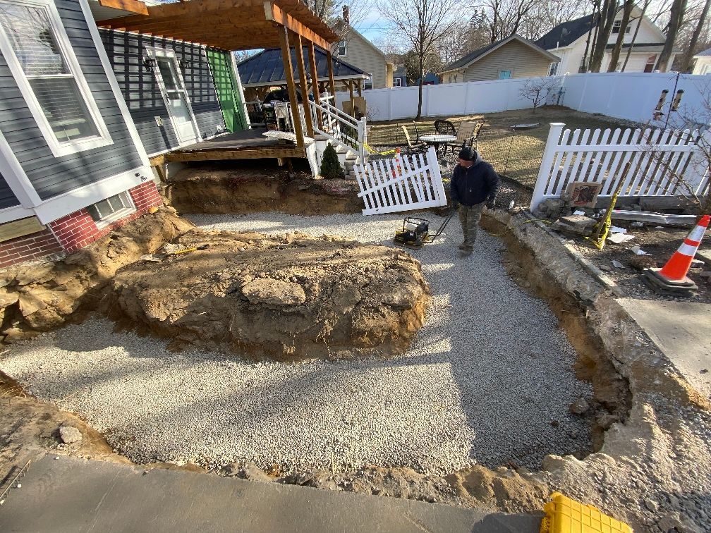 A man is digging a hole in the ground in front of a house.