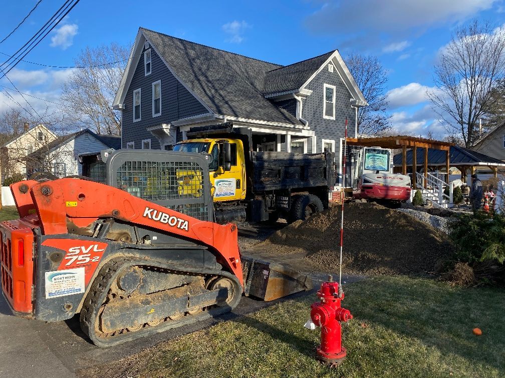 A bulldozer is parked in front of a house next to a fire hydrant.