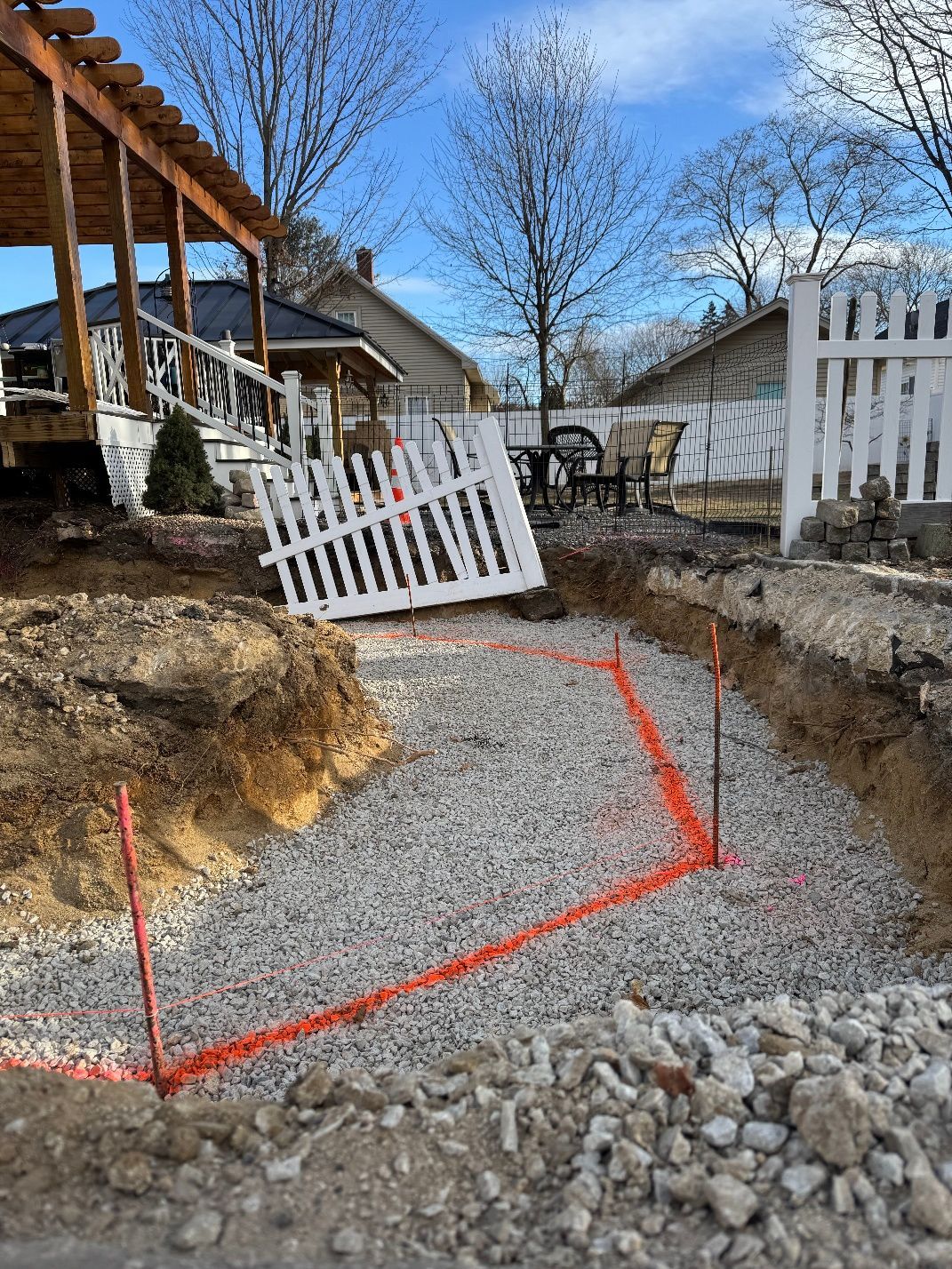A white fence is sitting on top of a pile of gravel in front of a house.