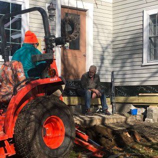 Worker Excavating Backyard While Owner is Watching