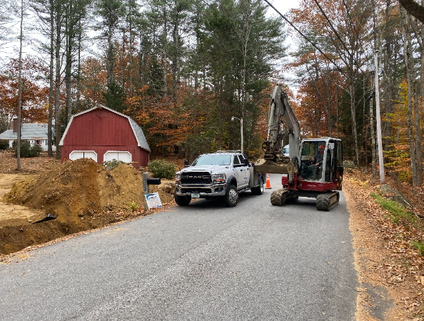 A truck and an excavator are parked on the side of a road.