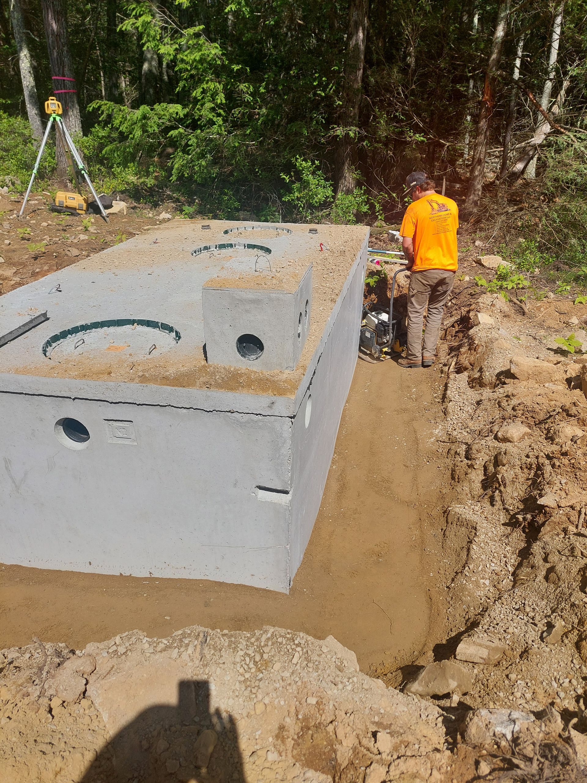 A man is working on a septic tank in the dirt.