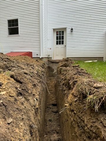 A large trench is being dug in front of a house.